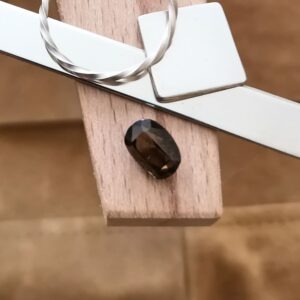 The brown zircon displayed on a jewellers bench peg with some sterling silver sheet and wire.