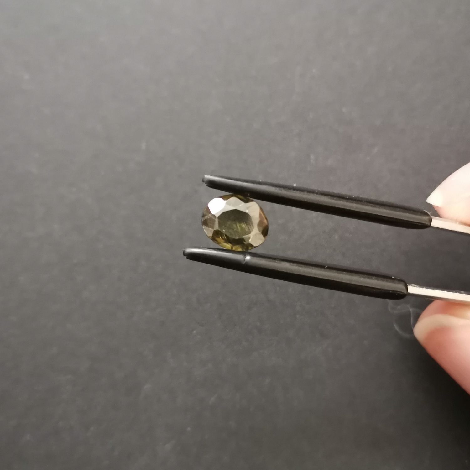 Crown view of the faceted oval zircon against a black background.