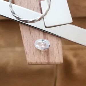 The clear zircon oval displayed on a jewellers bench peg with some sterling silver sheet and wire.