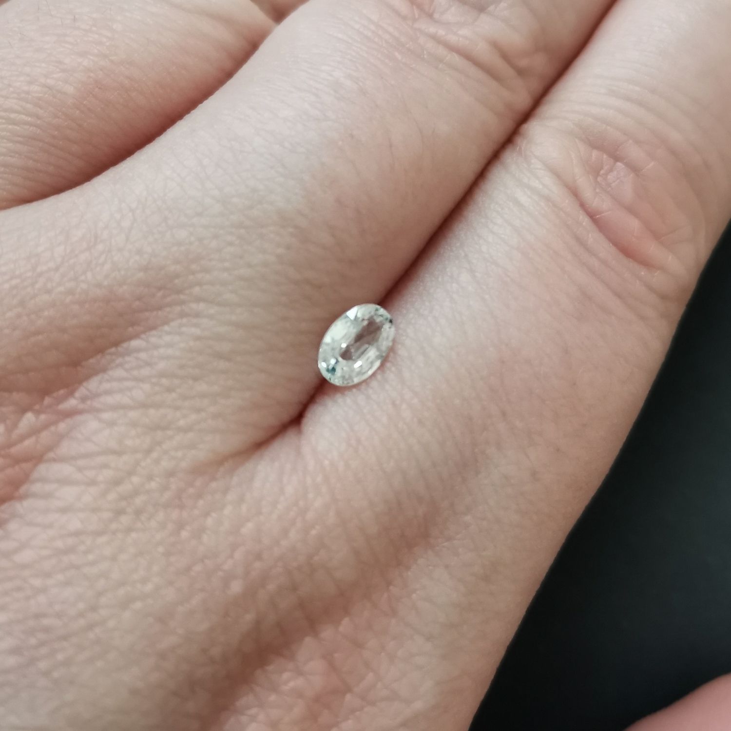 The faceted oval zircon resting on a hand to show size and colour.