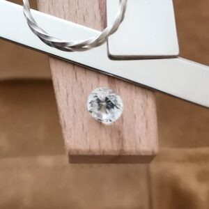 The white zircon round displayed on a jewellers bench peg with some sterling silver sheet and wire.