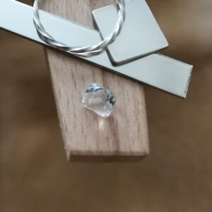 The clear quartz square displayed on a jewellers bench peg with some sterling silver sheet and wire.