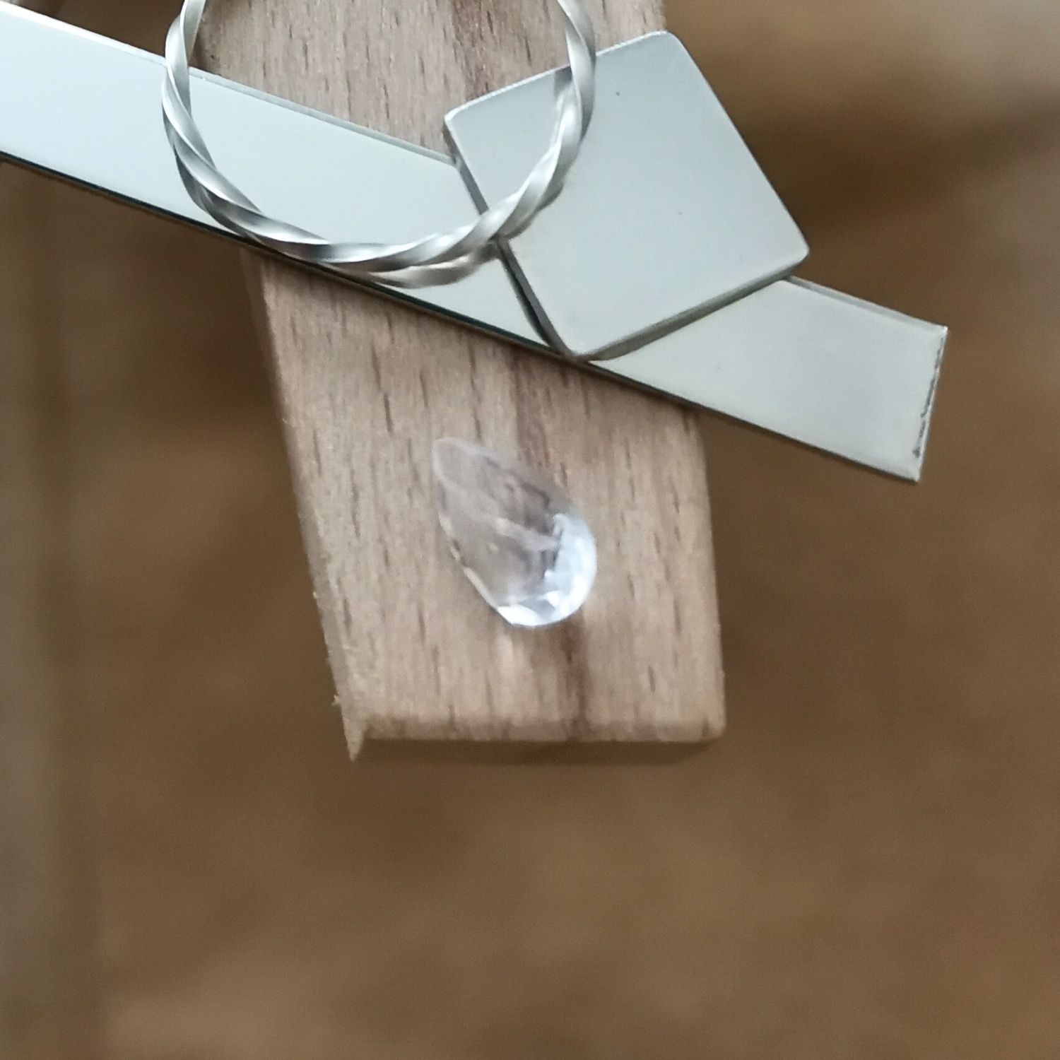 The clear quartz teardrop displayed on a jewellers bench peg with some sterling silver sheet and wire.