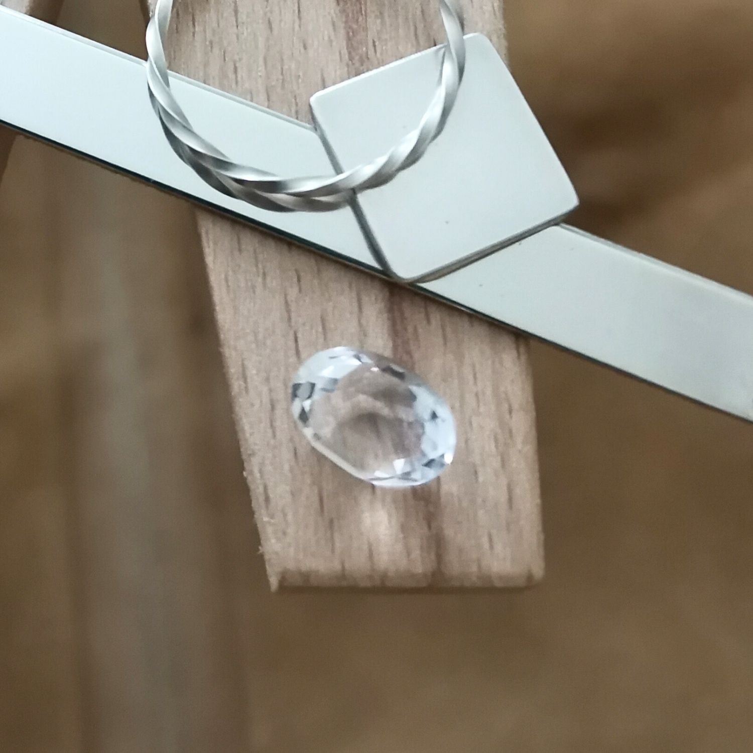The clear quartz oval displayed on a jewellers bench peg with some sterling silver sheet and wire.