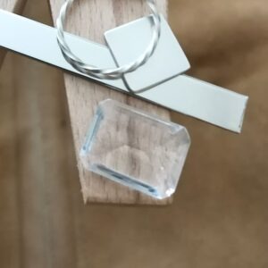The clear quartz rectangle displayed on a jewellers bench peg with some sterling silver sheet and wire.