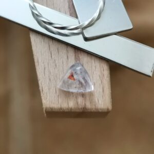 The Clear Quartz triangle displayed on a jewellers bench peg with some sterling silver sheet and wire.