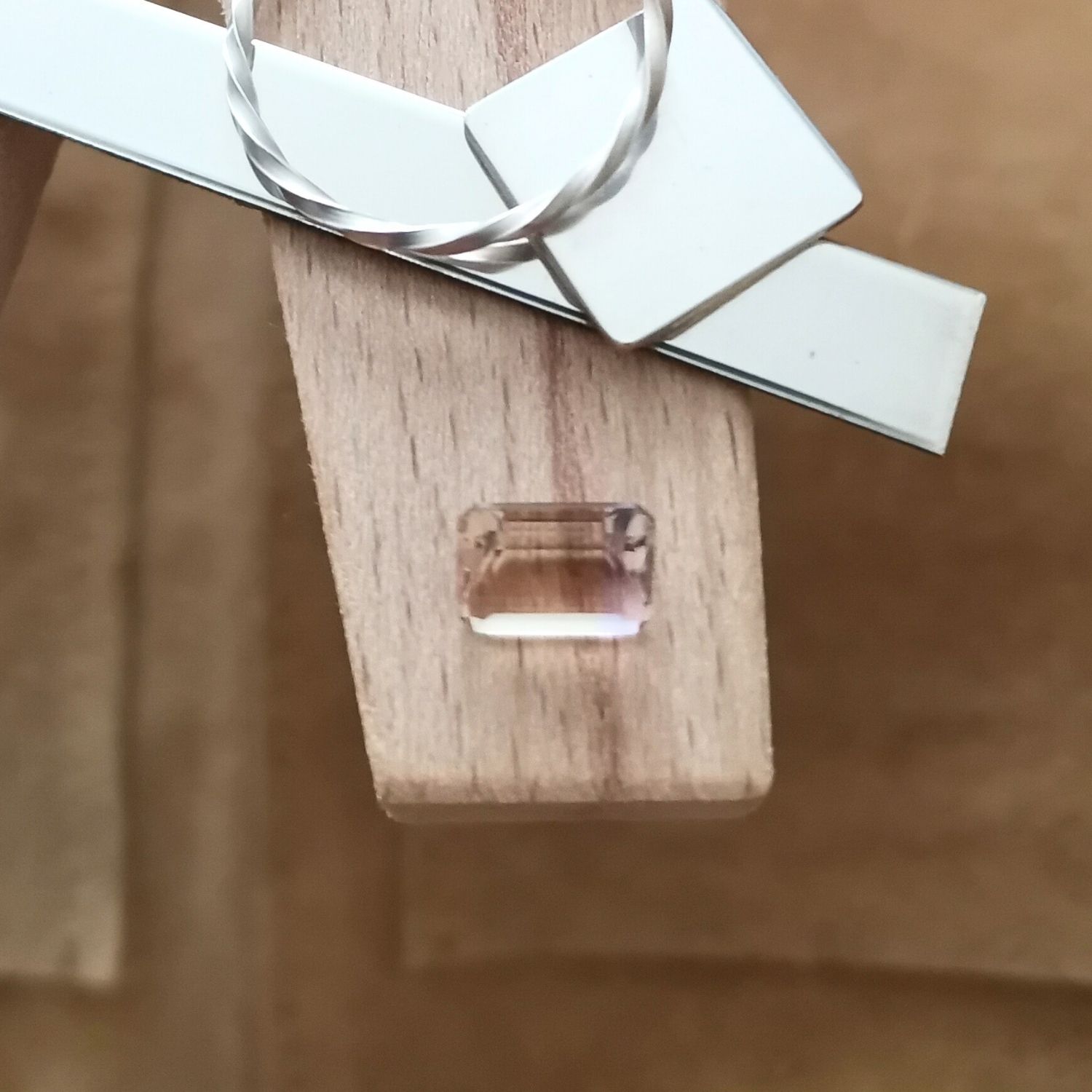 The yellow and purple ametrine rectangle displayed on a jewellers bench peg with some sterling silver sheet and wire.