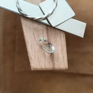 The yellowish green prasiolite rectangle displayed on a jewellers bench peg with some sterling silver sheet and wire.