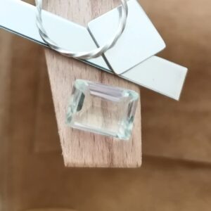 The yellowish green prasiolite rectangle displayed on a jewellers bench peg with some sterling silver sheet and wire.