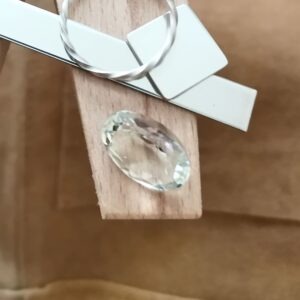 The yellowish green prasiolite oval displayed on a jewellers bench peg with some sterling silver sheet and wire.