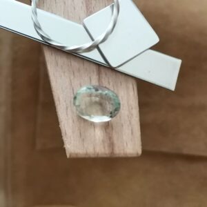 The yellowish green prasiolite oval displayed on a jewellers bench peg with some sterling silver sheet and wire.