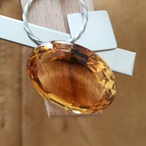 The large orange citrine oval displayed on a jewellers bench peg with some sterling silver sheet and wire.