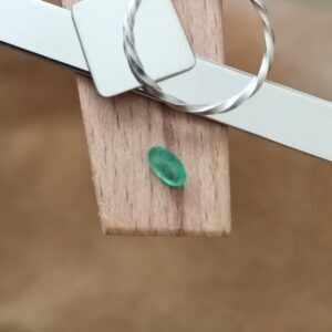 The green emerald oval displayed on a jewellers bench peg with some sterling silver sheet and wire.