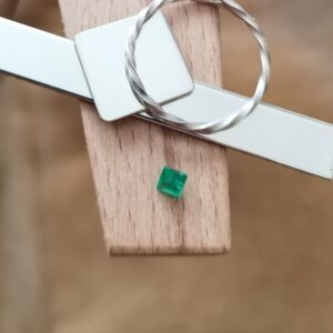 The green emerald square displayed on a jewellers bench peg with some sterling silver sheet and wire.