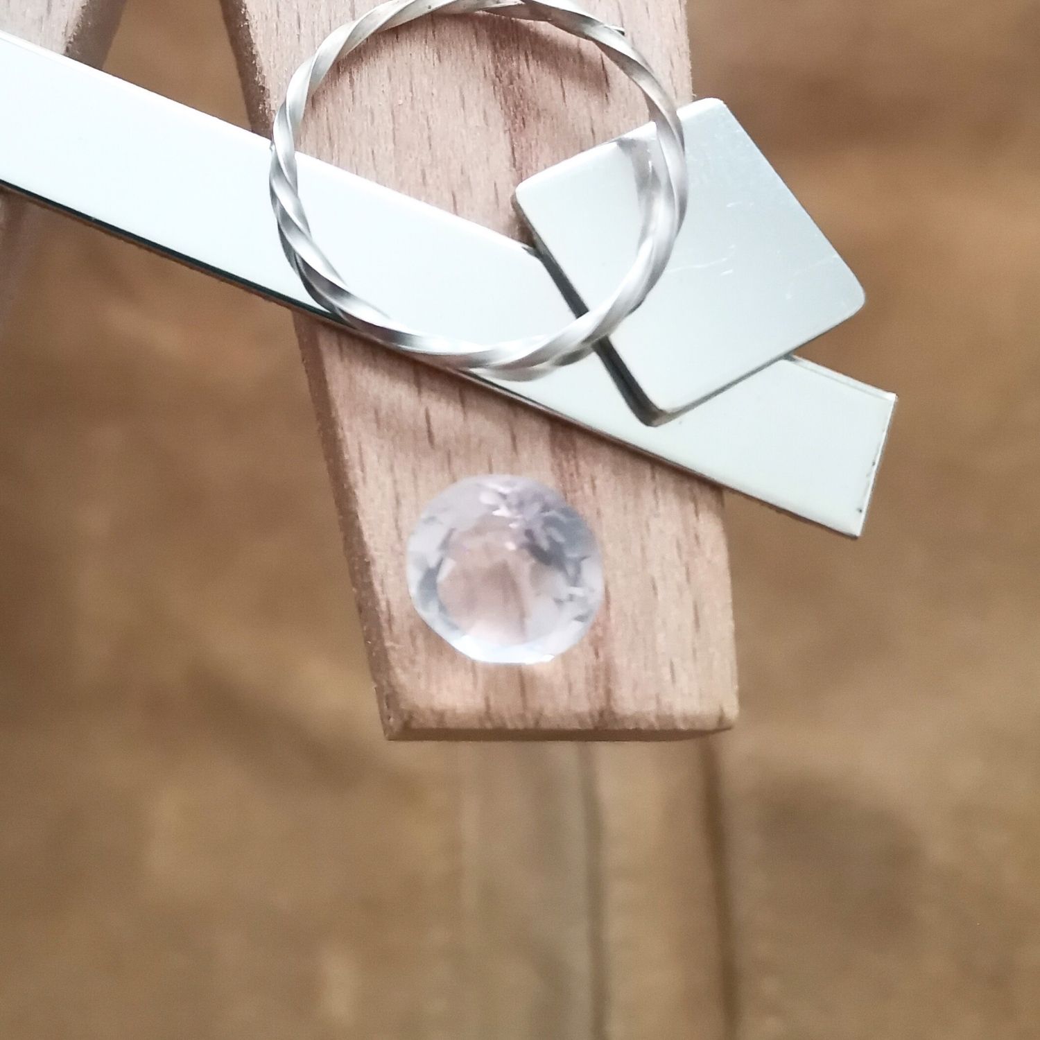 The pale pink rose quartz round displayed on a jewellers bench peg with some sterling silver sheet and wire.