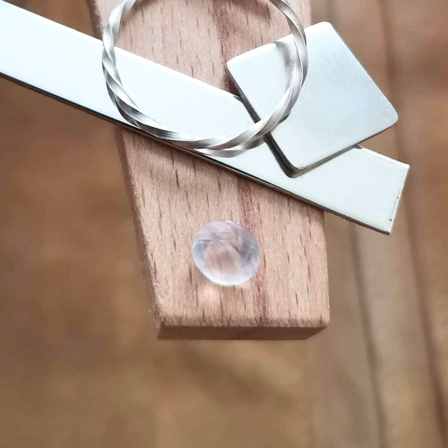 The pale pink rose quartz round displayed on a jewellers bench peg with some sterling silver sheet and wire.