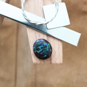 The small free-form boulder opal displayed on a jewellers bench peg with some sterling silver sheet and wire.