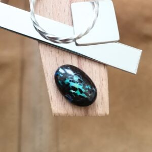 The small free-form boulder opal displayed on a jewellers bench peg with some sterling silver sheet and wire.