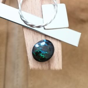 The small free-form boulder opal displayed on a jewellers bench peg with some sterling silver sheet and wire.