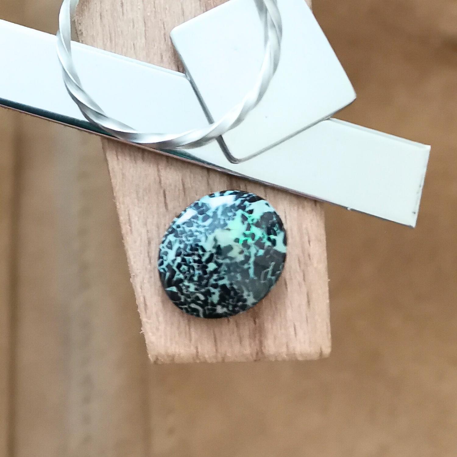The small free-form boulder opal displayed on a jewellers bench peg with some sterling silver sheet and wire.