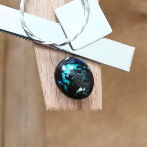 The small free-form boulder opal displayed on a jewellers bench peg with some sterling silver sheet and wire.