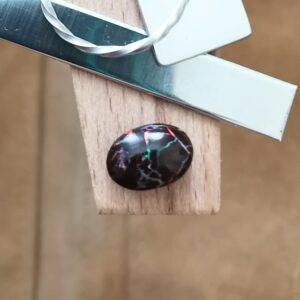 The small free-form boulder opal displayed on a jewellers bench peg with some sterling silver sheet and wire.