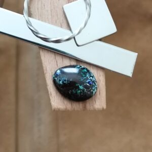 The small free-form boulder opal displayed on a jewellers bench peg with some sterling silver sheet and wire.