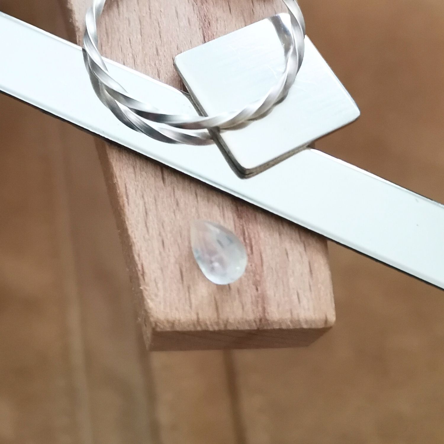 The moonstone teardrop displayed on a jewellers bench peg with some sterling silver sheet and wire.