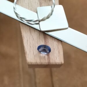The vilet iolite oval displayed on a jewellers bench peg with some sterling silver sheet and wire.