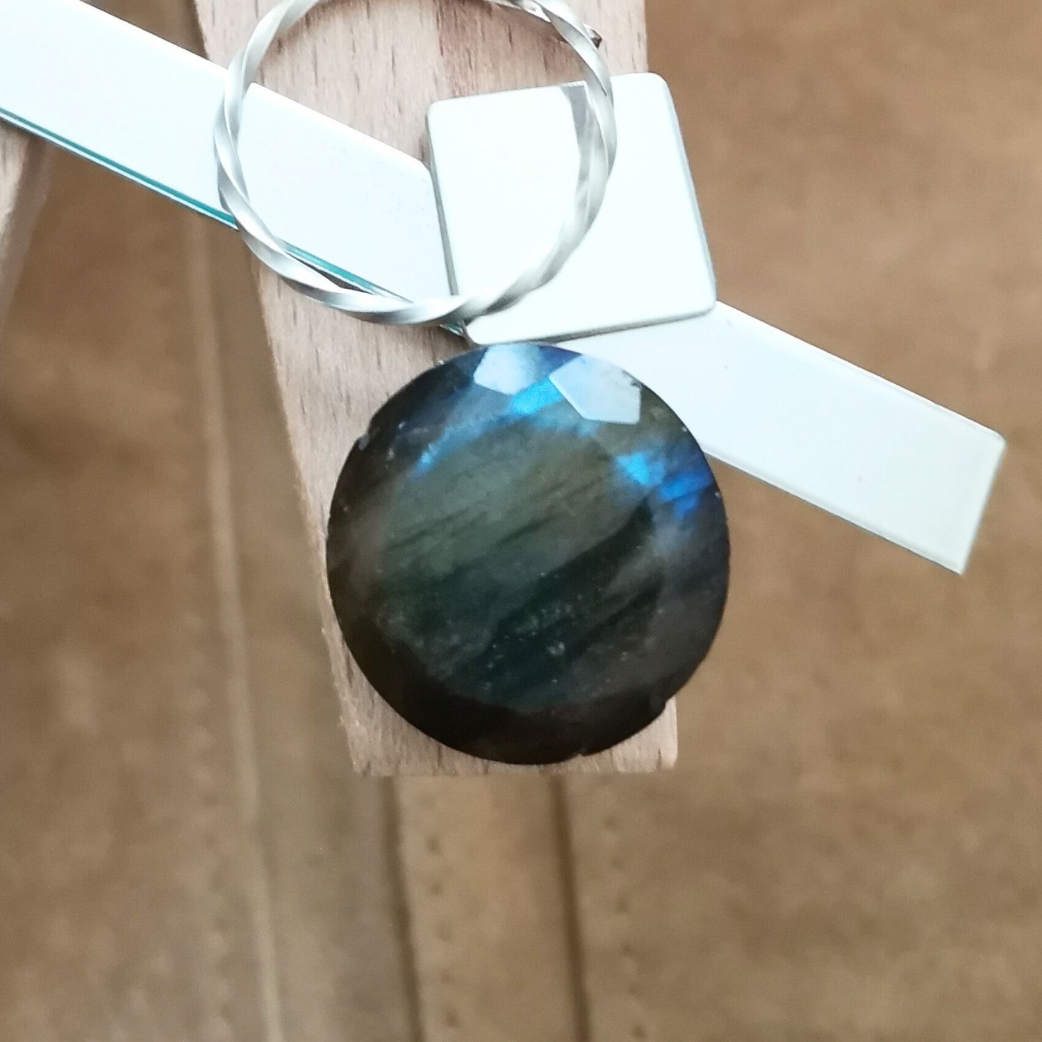 The large labradorite round displayed on a jewellers bench peg with some sterling silver sheet and wire.