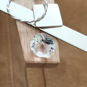 The Clear Quartz faceted round displayed on a jewellers bench peg with some sterling silver sheet and wire.