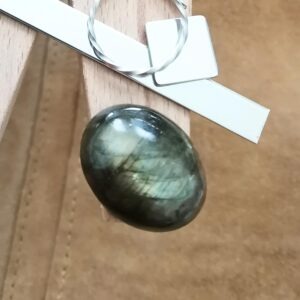 The oval labradorite cabochon displayed on a jewellers bench peg with some sterling silver sheet and wire.