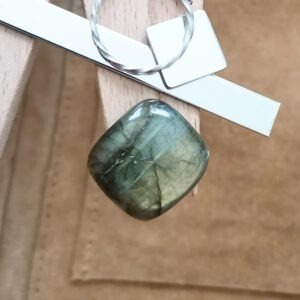 The rectangle labradorite cabochon displayed on a jewellers bench peg with some sterling silver sheet and wire.