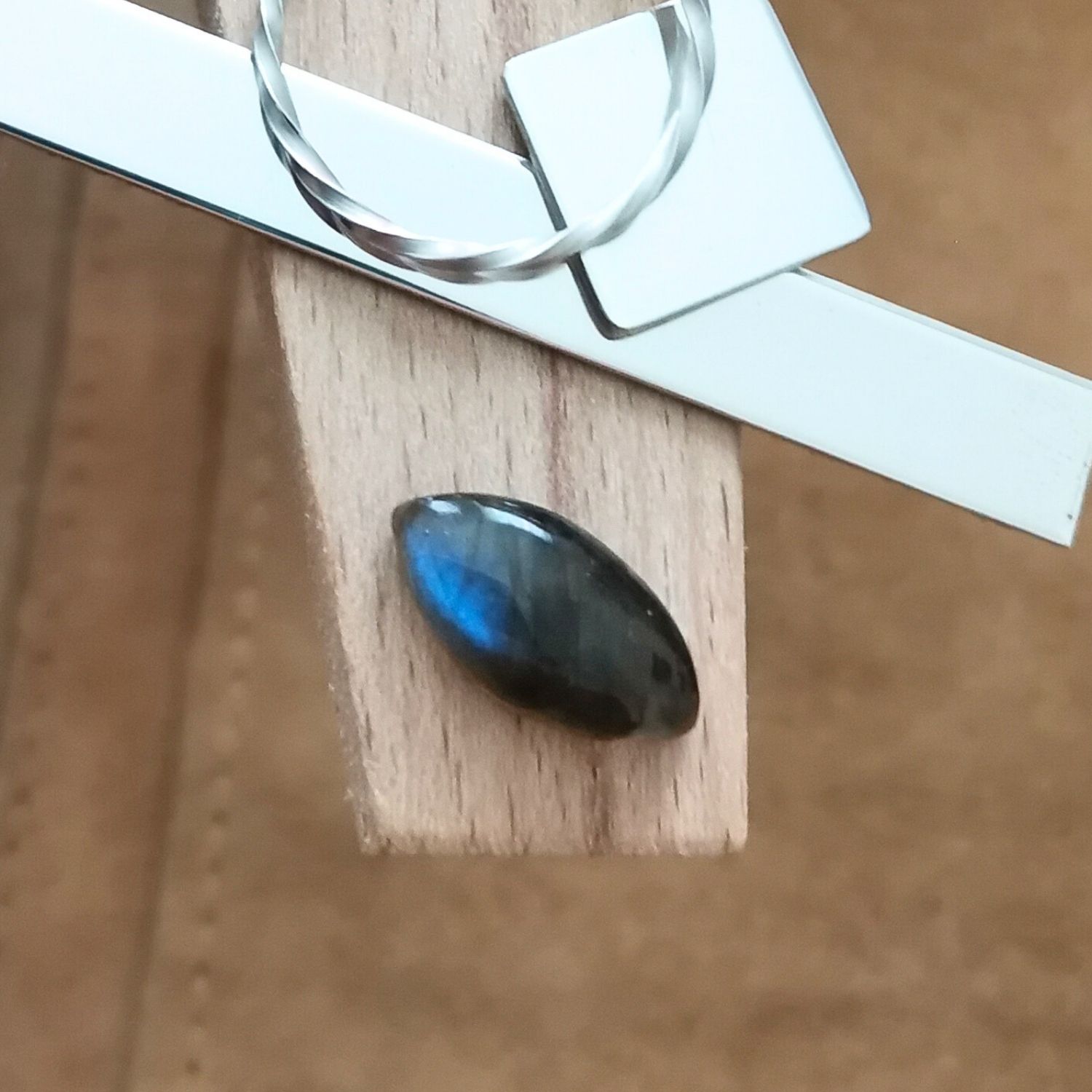 The marquise labradorite cabochon displayed on a jewellers bench peg with some sterling silver sheet and wire.