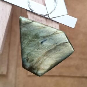 The large freeform labradorite cabochon displayed on a jewellers bench peg with some sterling silver sheet and wire.