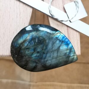 The large freeform labradorite cabochon displayed on a jewellers bench peg with some sterling silver sheet and wire.