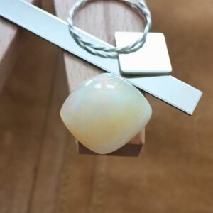 The yellow free form opal cabochon displayed on a jewellers bench peg with some sterling silver sheet and wire.