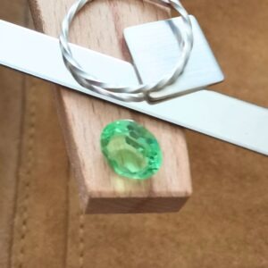 The green uranium glass oval displayed on a jewellers bench peg with some sterling silver sheet and wire.