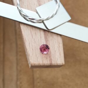 The deep pink round topaz displayed on a jewellers bench peg with some sterling silver sheet and wire.