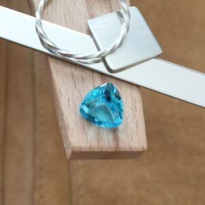 The blue topaz triangle displayed on a jewellers bench peg with some sterling silver sheet and wire.