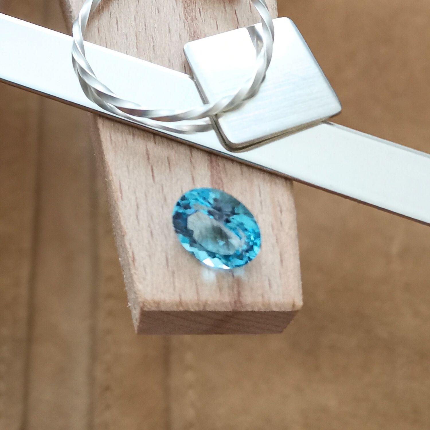 The swiss blue topaz oval displayed on a jewellers bench peg with some sterling silver sheet and wire.