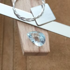 The teardrop goshenite displayed on a jewellers bench peg with some sterling silver sheet and wire.
