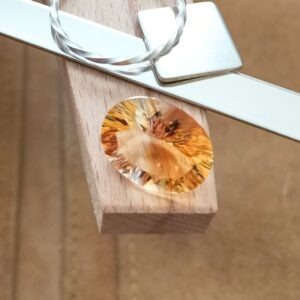 The orange citrine oval displayed on a jewellers bench peg with some sterling silver sheet and wire.