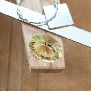 The yellow citrine oval displayed on a jewellers bench peg with some sterling silver sheet and wire.