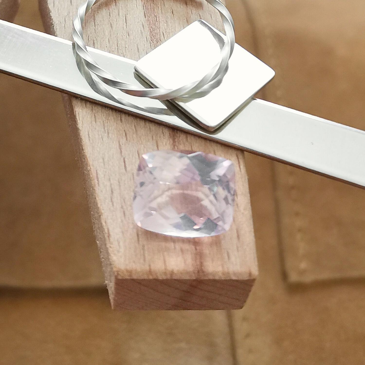 The checkerboard pale pink rose quartz rectangle displayed on a jewellers bench peg with some sterling silver sheet and wire.