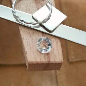 The clear quartz round displayed on a jewellers bench peg with some sterling silver sheet and wire.