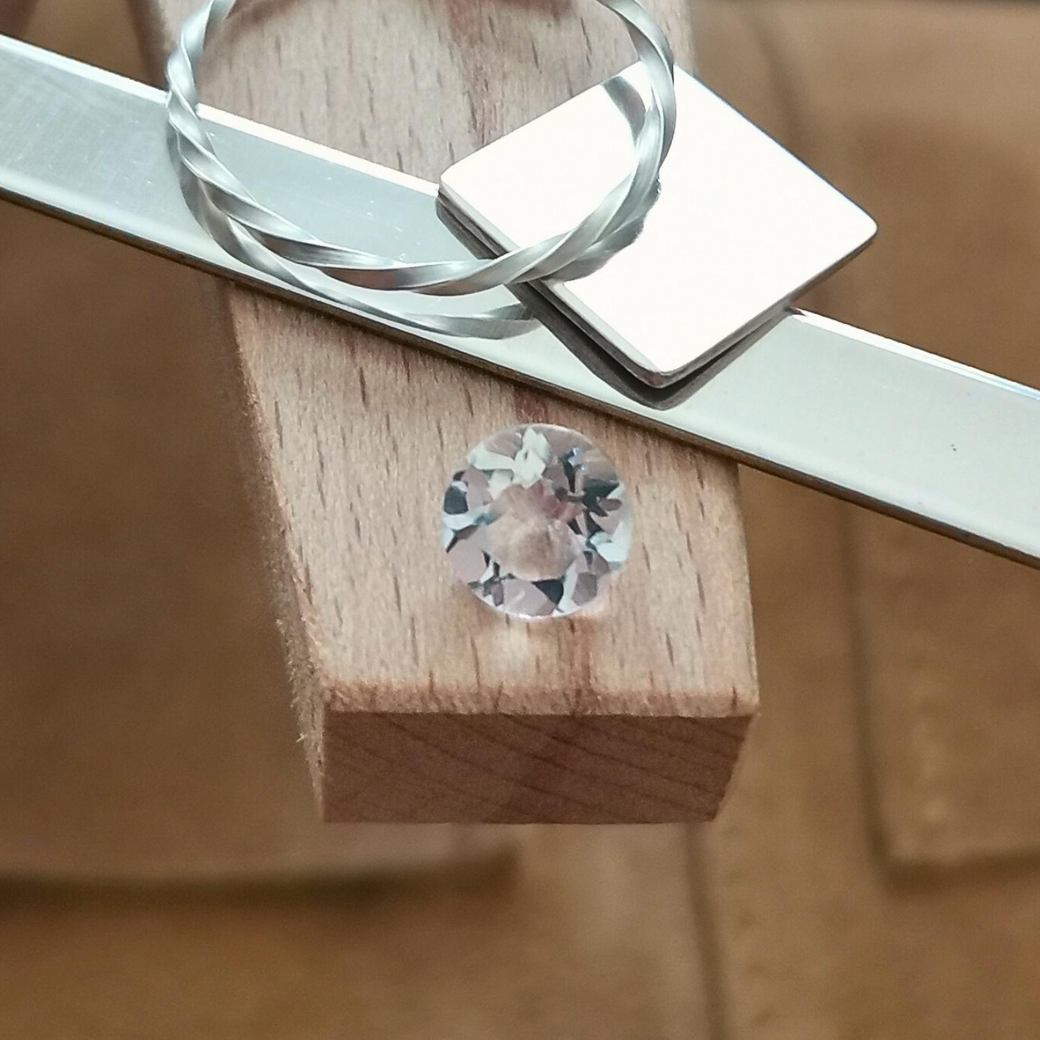 The clear quartz round displayed on a jewellers bench peg with some sterling silver sheet and wire.