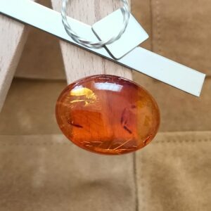 The large oval amber cabochon displayed on a jewellers bench peg with some sterling silver sheet and wire.