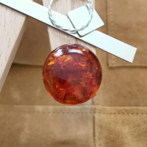 The large round amber cabochon displayed on a jewellers bench peg with some sterling silver sheet and wire.