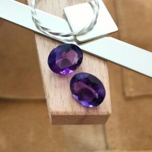The pair of deep purple amethyst ovals displayed on a jewellers bench peg with some sterling silver sheet and wire.